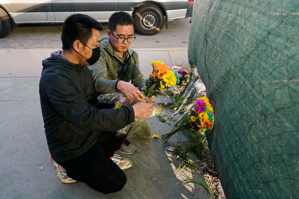 Two men place flowers near Star Dance Studio to honor victims killed in a shooting in Monterey...
