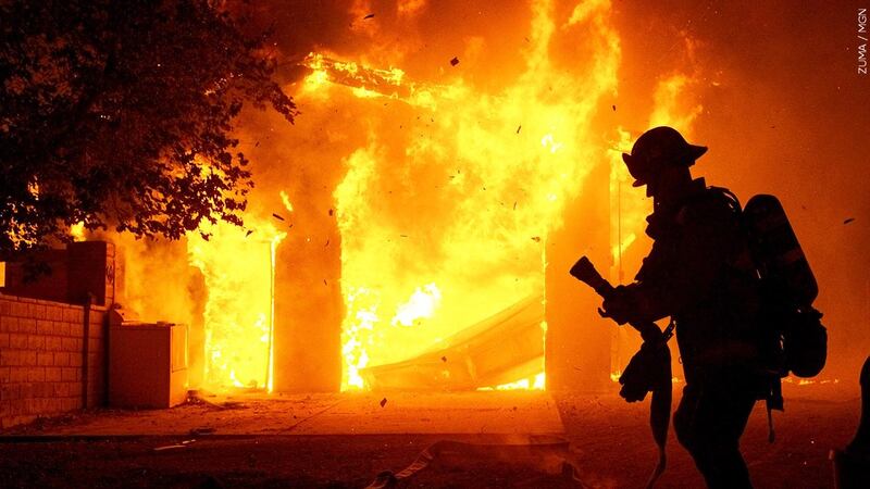 FILE — A firefighter prepares to put water on a fully engulfed house fire in Canyon Country,...
