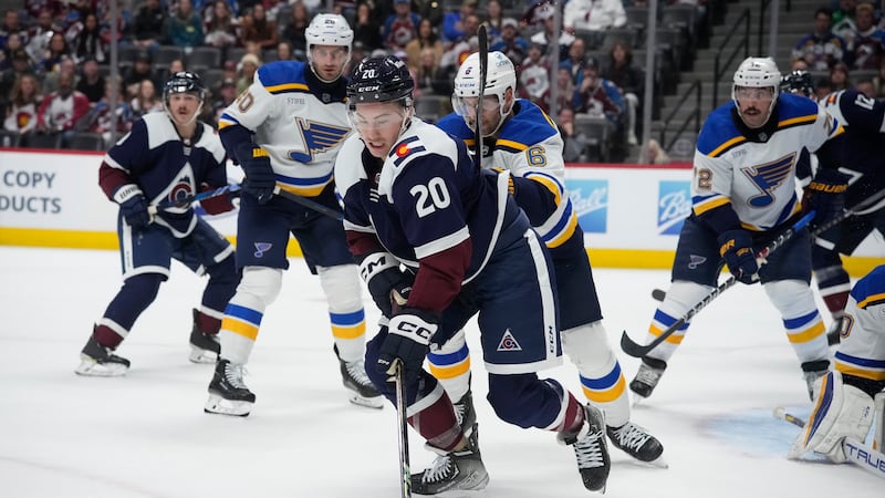 Colorado Avalanche center Ross Colton, front, passes the puck as St. Louis Blues defenseman...