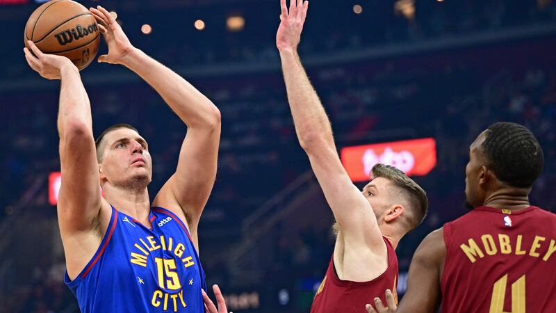 Denver Nuggets center Nikola Jokic, left, shoots against Cleveland Cavaliers forward Dean...